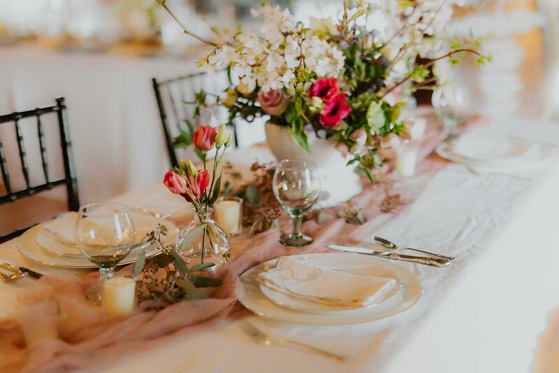 Decorative table setting with flowers and plates on a white tablecloth.